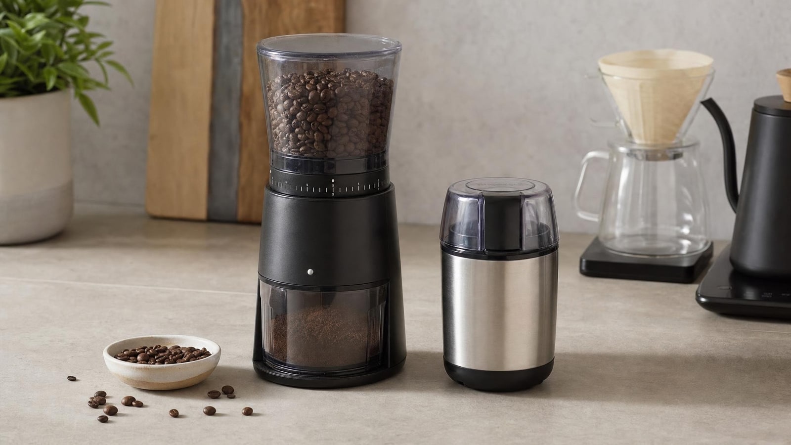 A calm coffee station showing generic countertop burr-grinder and compact blade-grinder silhouettes as category examples, beans loose in a small bowl, no brands